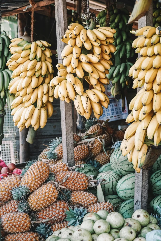 Fresh tropical fruits at a local Sri Lankan market, including bananas, pineapples, and watermelons.