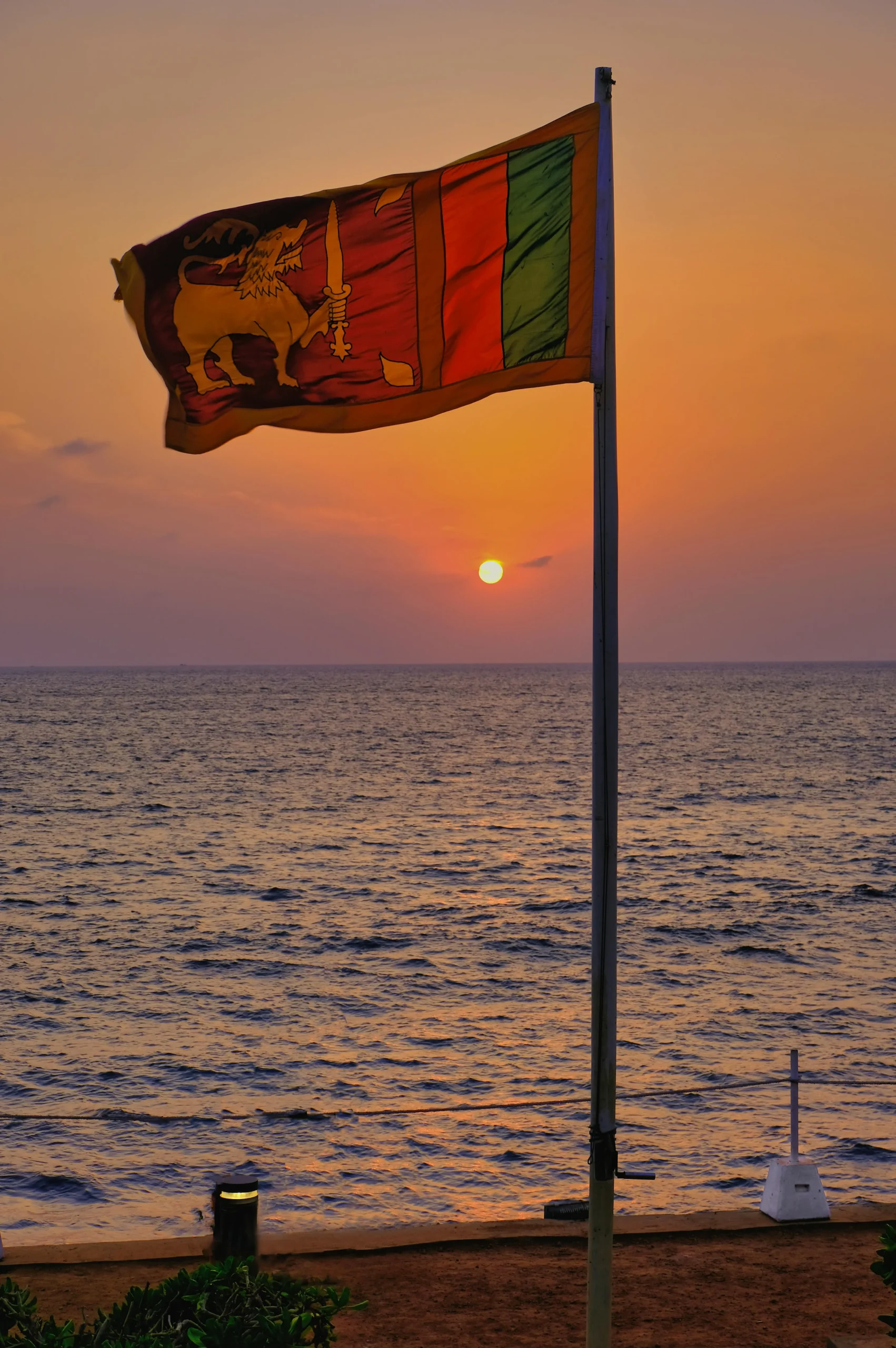 Sri Lankan national flag at Galle Face Green during sunset over the Indian Ocean in Colombo