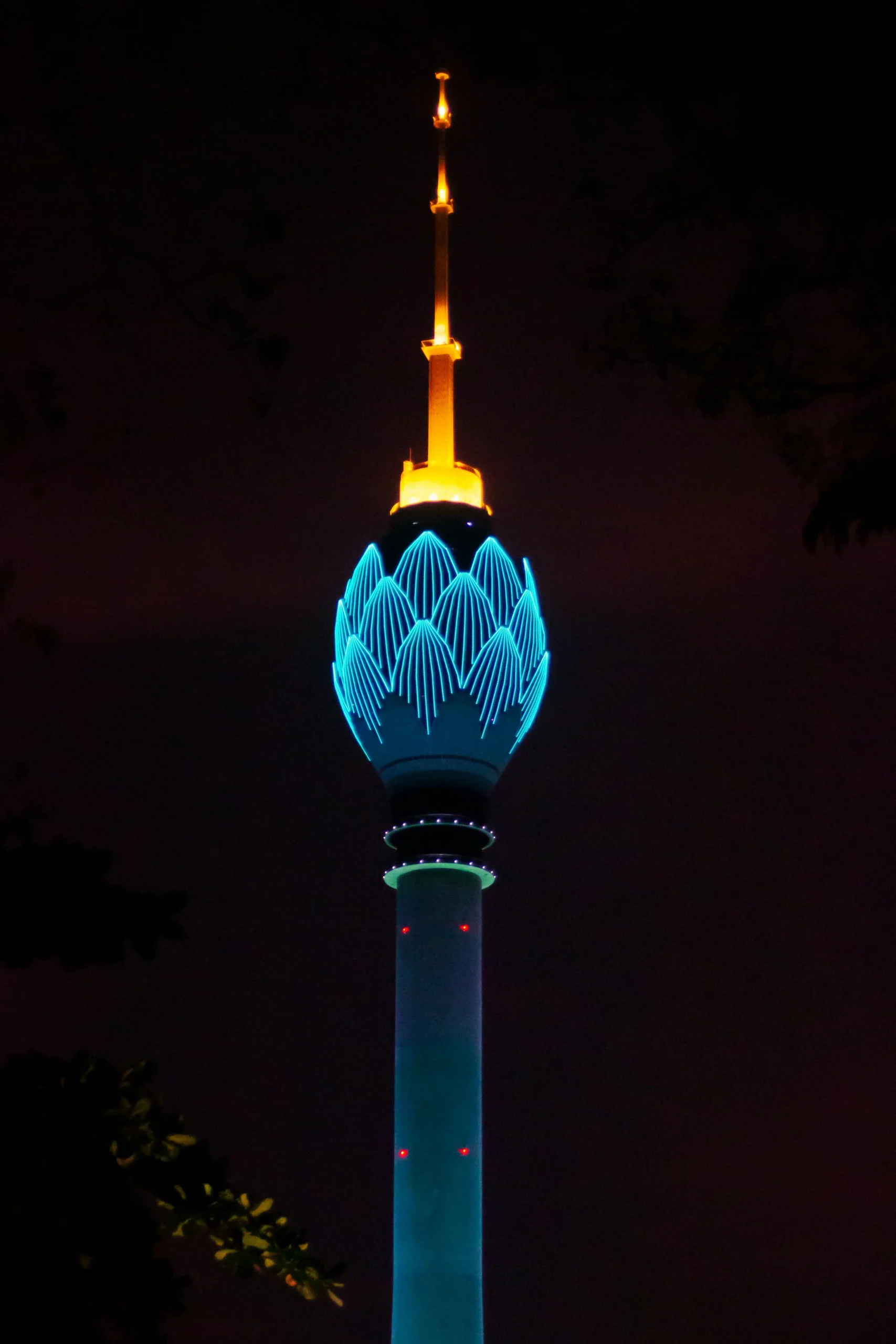Colombo Lotus Tower illuminated at night with vibrant blue and golden lights against a dark sky